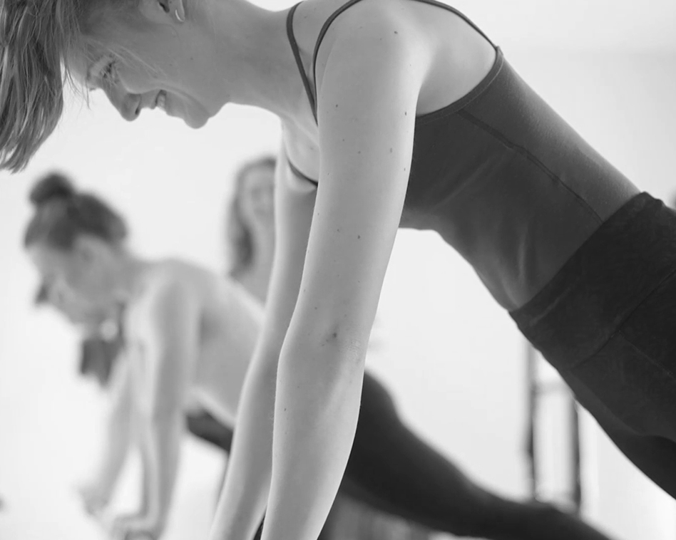 A group of women laughing and enjoying pilates reformer training