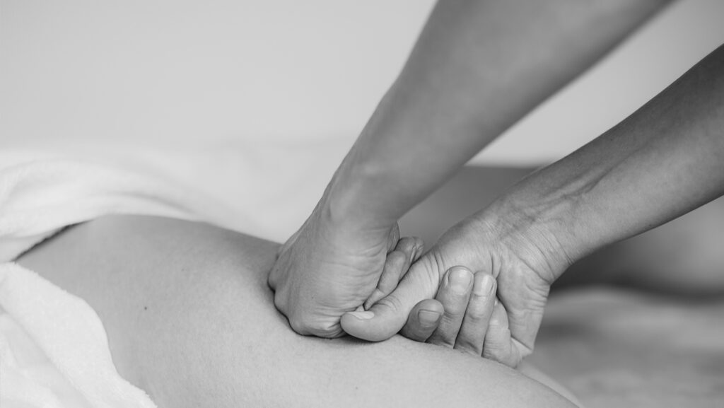 Massagebehandlung, Faszienbehandlung für den Oberschenkel. Der Oberschenkel wird mit beiden Händen massiert. Sportmassage. Heilmassage-Behandlung.