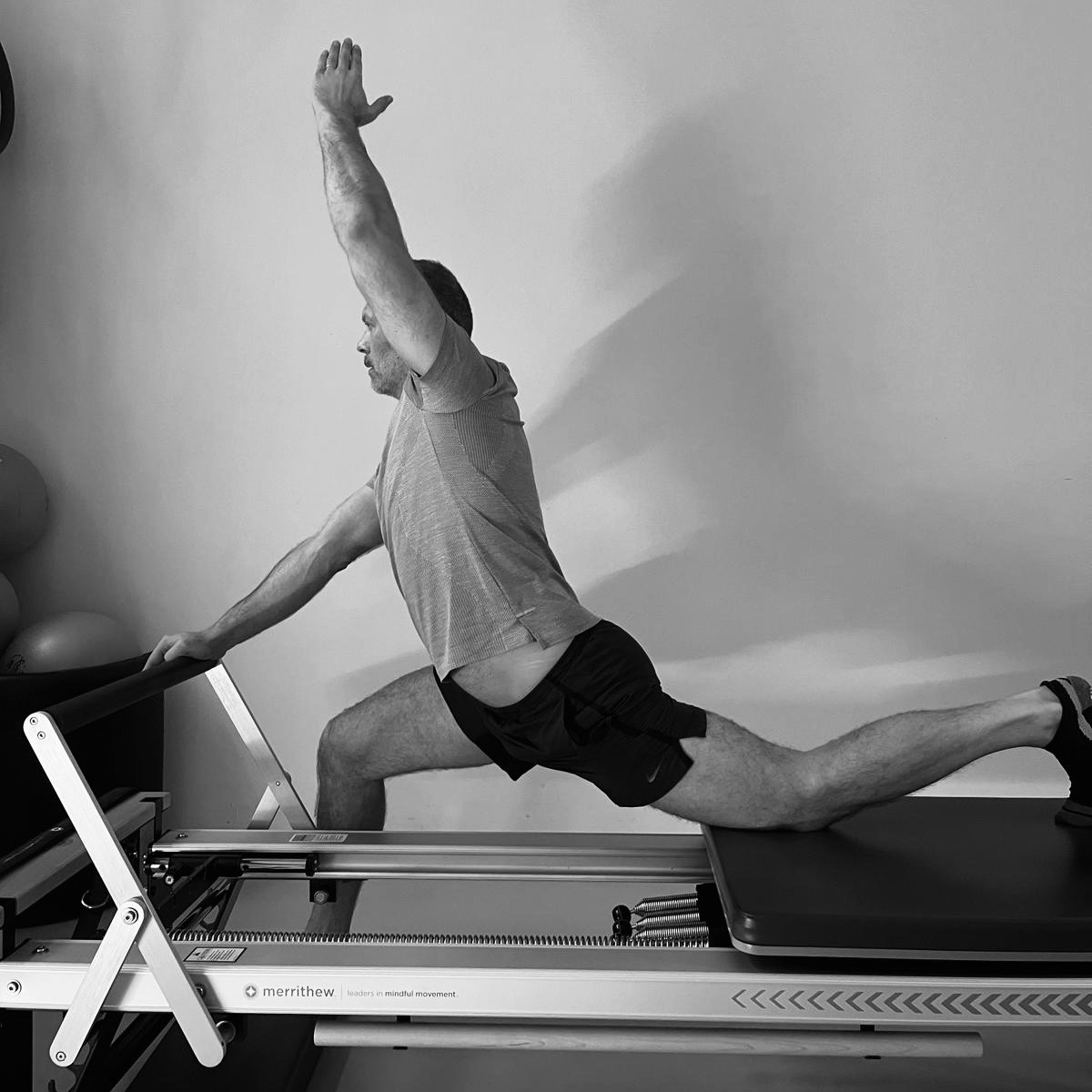 Flexibility for men. Pilates training on the Pilates reformer, a man stretches and opens up the entire left side of his body.