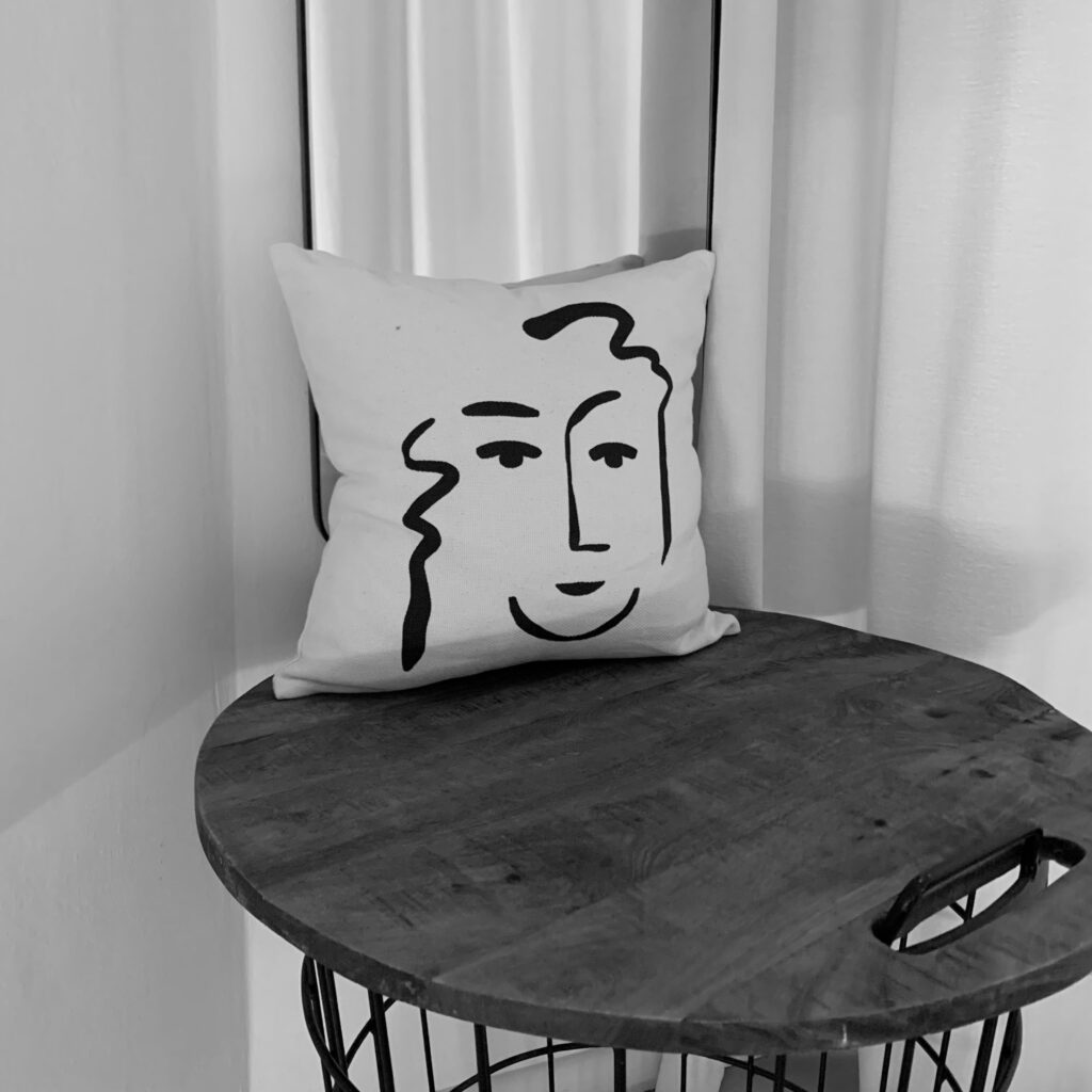 Pillow in the locker room of a Pilates studio with a face as an illustration on it.
