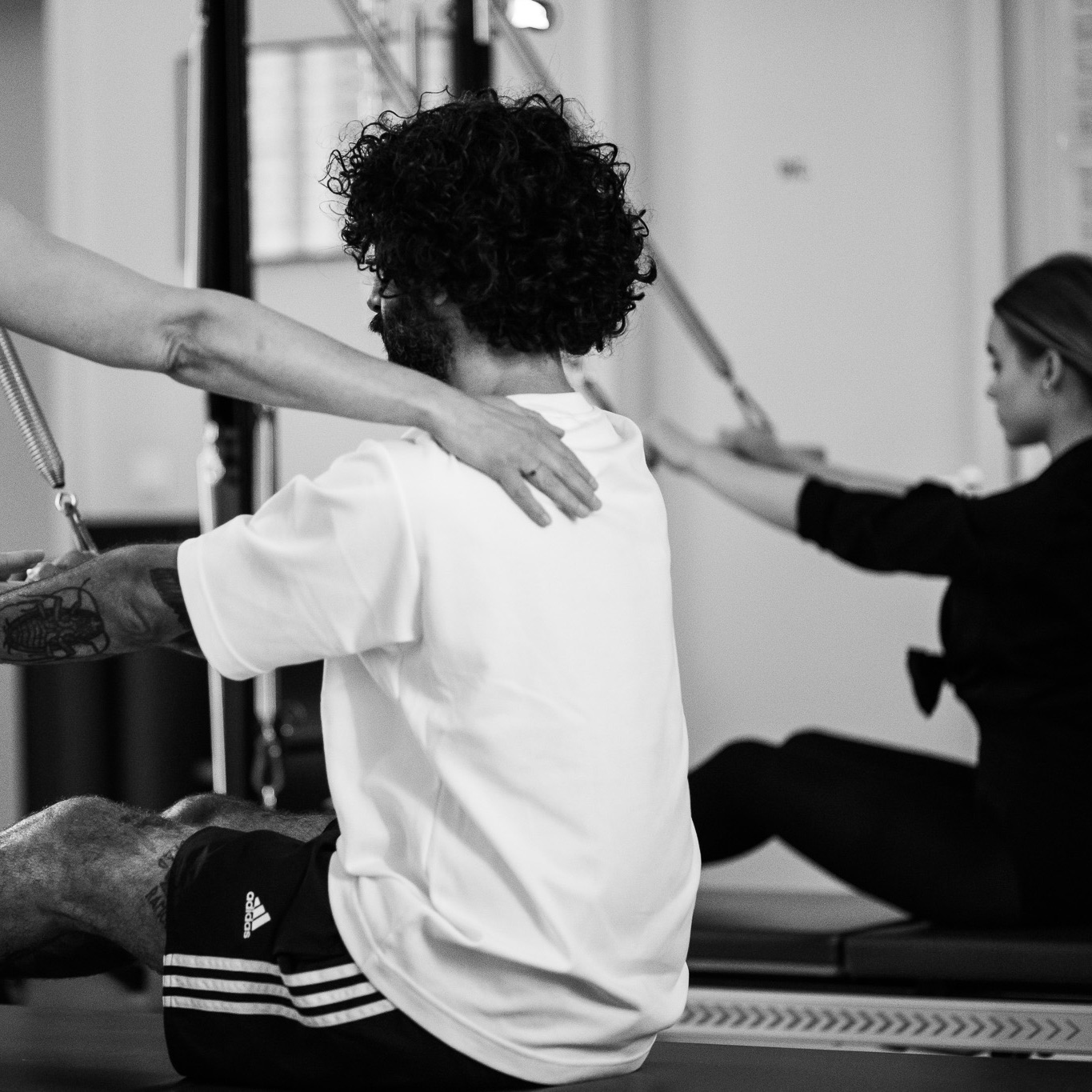 A young man trains upright posture on the Pilates Tower Unit Wall. Strengthen your back and posture with Pilates training under the guidance of experienced Pilates instructors to prevent a slipped disc in the lower back. Pain-free with Pilates.