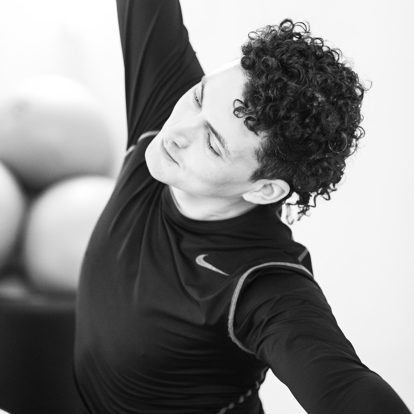 Wenn Stress auf den Schultern drückt, wie man Blockaden löst. EIn junger Mann trainiert seine Schulter Mobilisation im Pilates Training.Beide Arme sind gestreckt und sein Blick und Körper ist entspannt und kraftvoll.