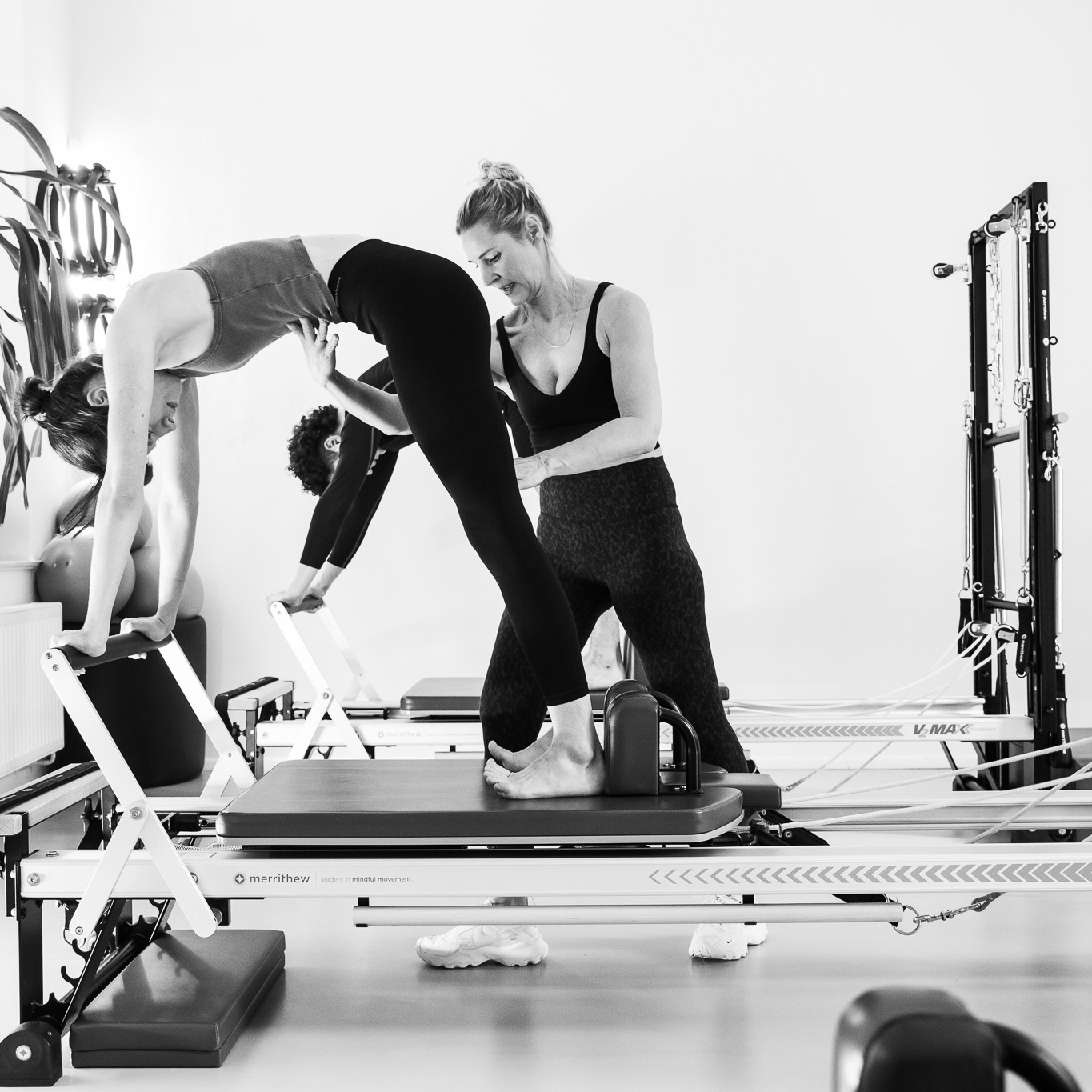 Eine junge Frau und ein junger Mann trainieren gemeinsam mit einer Pilates Training am Pilates Reformer. In einer Duo Pilates Klasse. Basierend auf den sechs Prinzipien im Pilates.