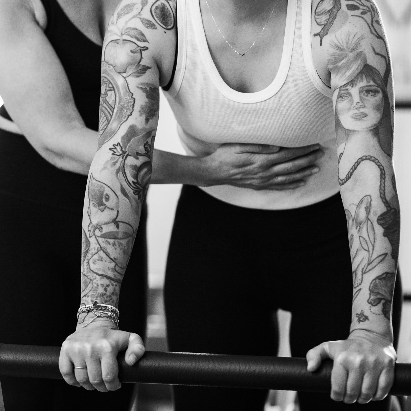 Core-Training im Pilates, am Reformer. Eine Klientin trainiert gemeinsam mit einer Pilates Lehrerin . Sie unterstützt zur Vorbereitung für die nächste Pilates Übung.