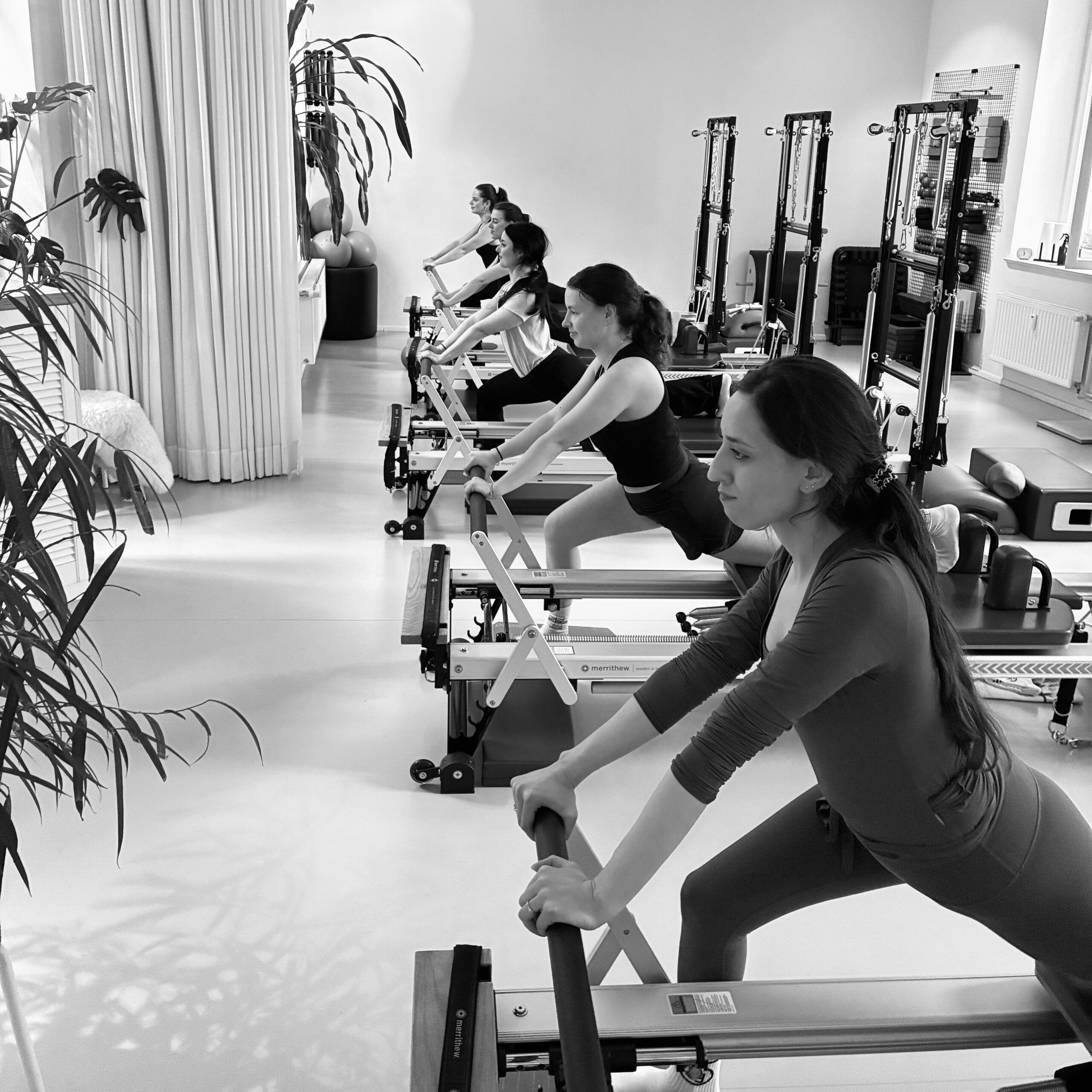 A team of young employees at a corporate Pilates event at the REALZ Pilates studio. Everyone is listening with enthusiasm and curiosity, dressed in sportswear.