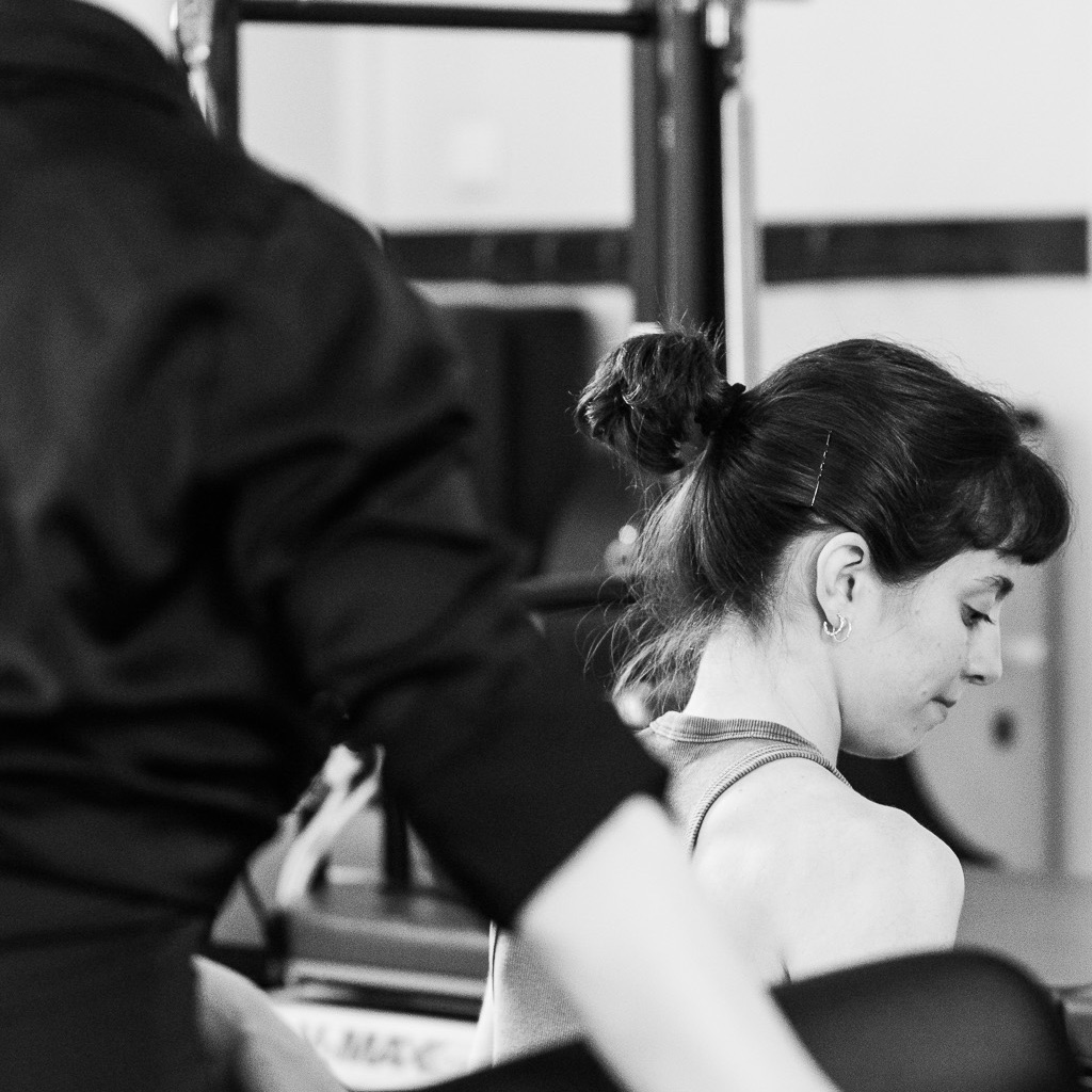 Junge Teilnehmerinnen im Pilates Workshop sind aufmerksam in der Masterclass dabei, sie nehmen die Informationen tief auf und sind ganz im Workshop, schreiben mit und sitzen direkt an den Geräten.